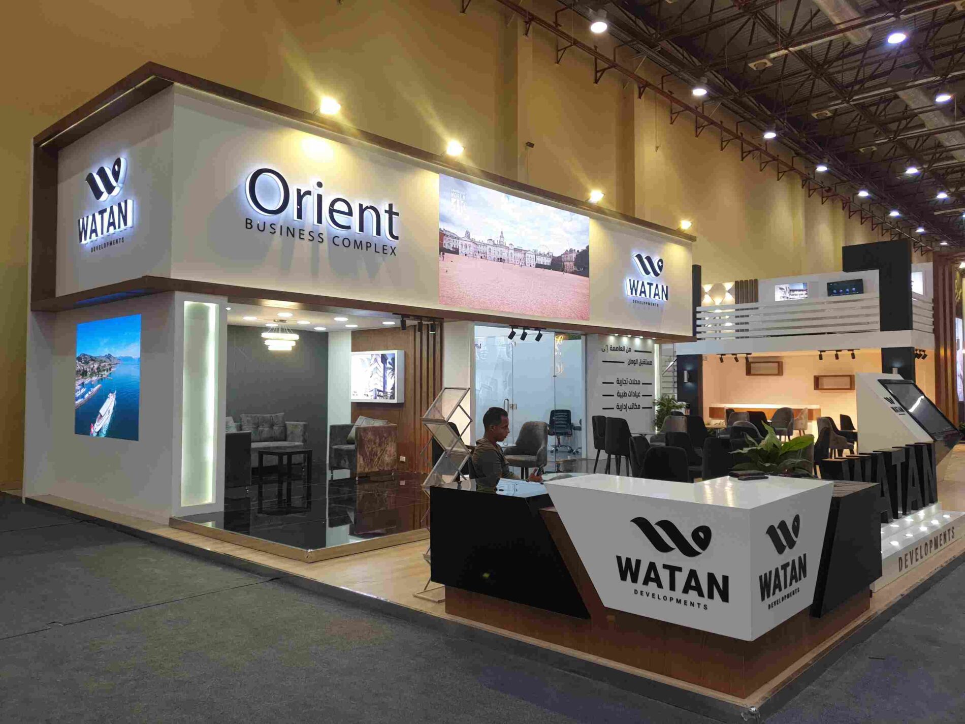 Watan Development booth at the Al-Ahram Real Estate Exhibition 2021, showcasing modern design and luxury with interactive displays and a welcoming atmosphere.