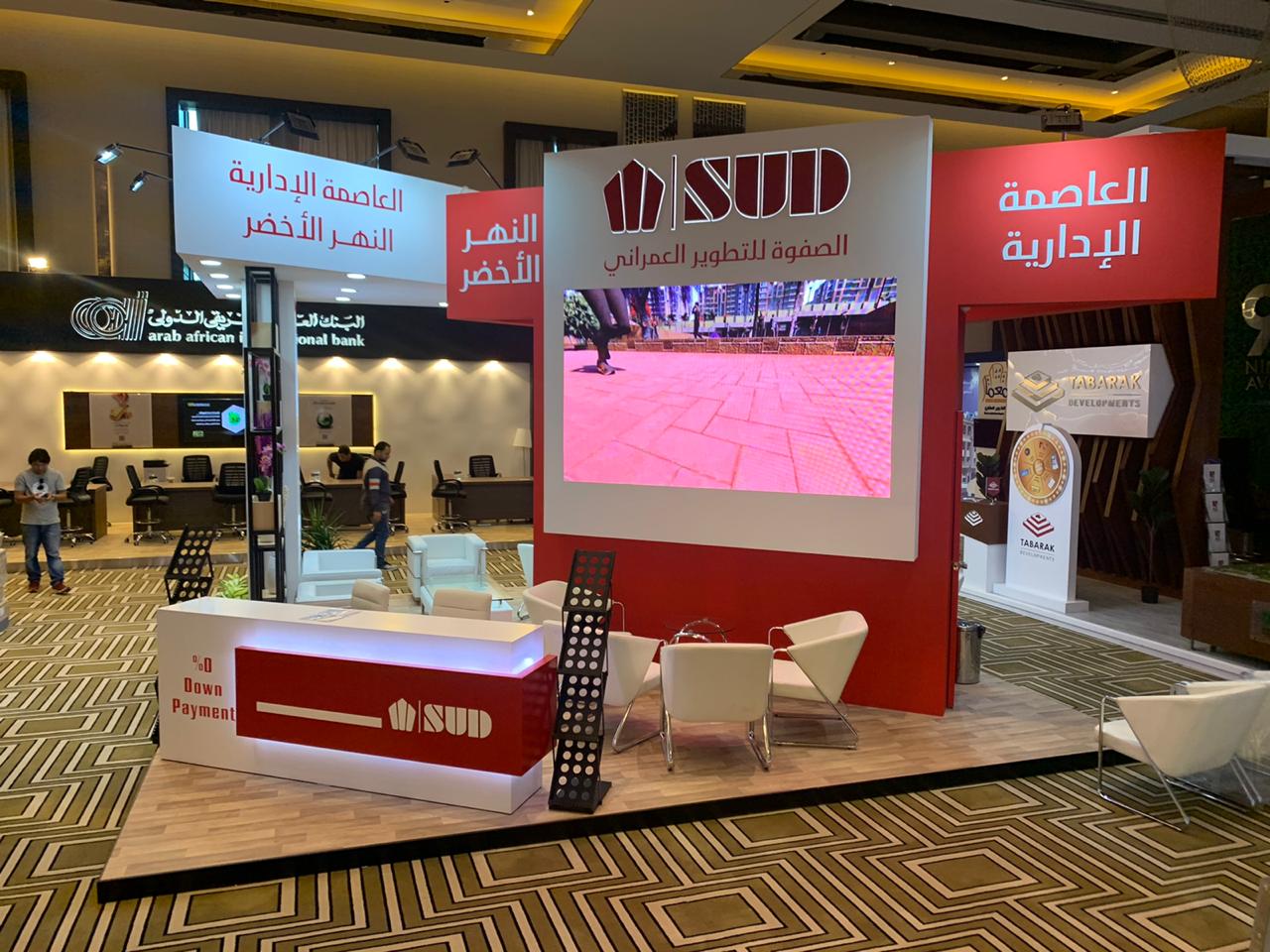 SUD booth at the International Property Show 2019 in Riyadh, featuring a sleek, modern design with high-quality materials, elegant architectural elements, and interactive displays showcasing luxury real estate.