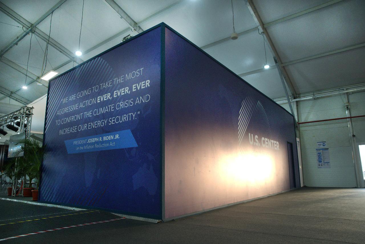 USA booth at COP27 in Sharm El Sheikh, showcasing a sleek design with prominent displays and multimedia presentations that emphasize the United States' climate policies, renewable energy advancements, and commitments to global climate action.